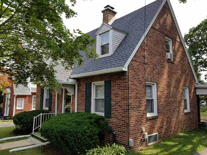 Brick Cape Cod home in York County with a new dark shingle roof by Dallastown Roofing