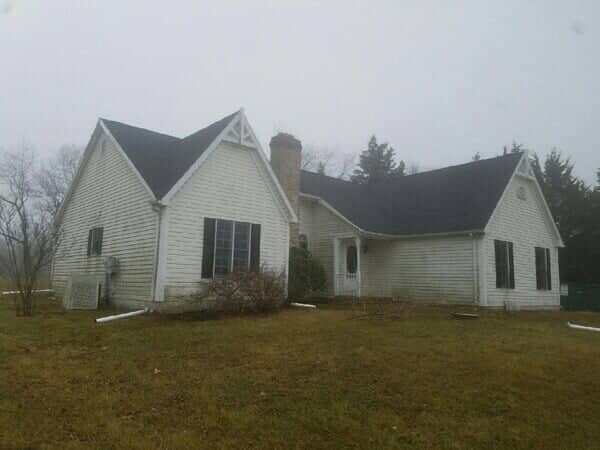 Older home on a wooded slope with a new roof in Glen Rock, PA