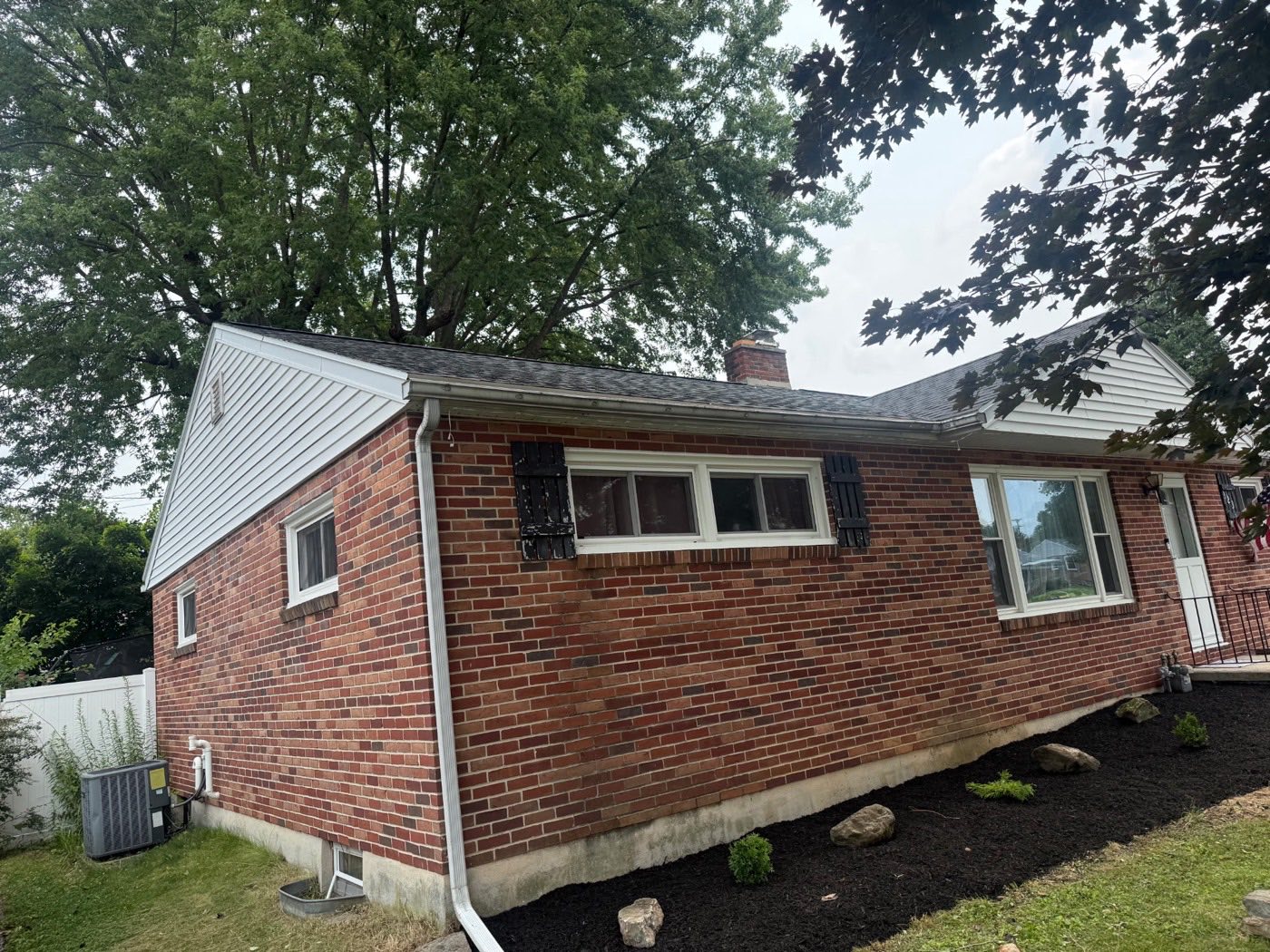 Brick ranch home with white-sided gable ends, a new dark shingle roof, and fresh mulch landscaping