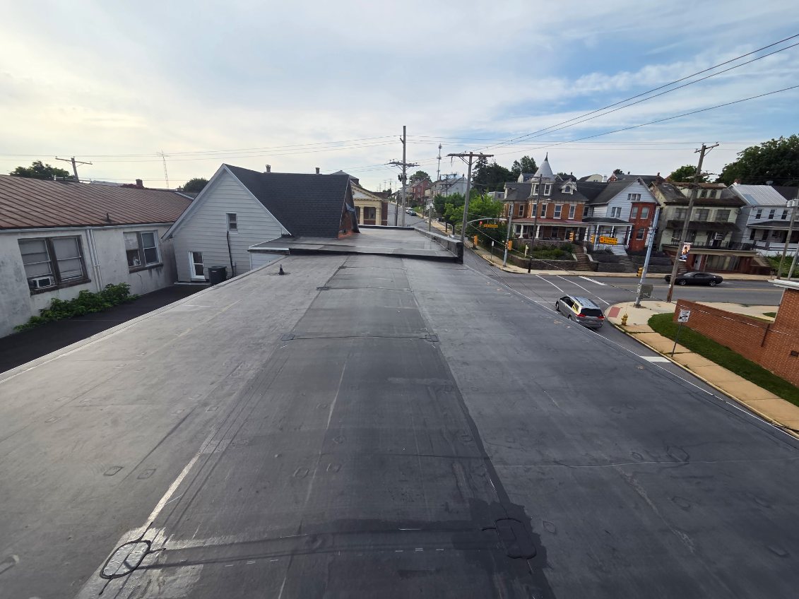 Large flat rubber roof on a downtown commercial building with a street view of town