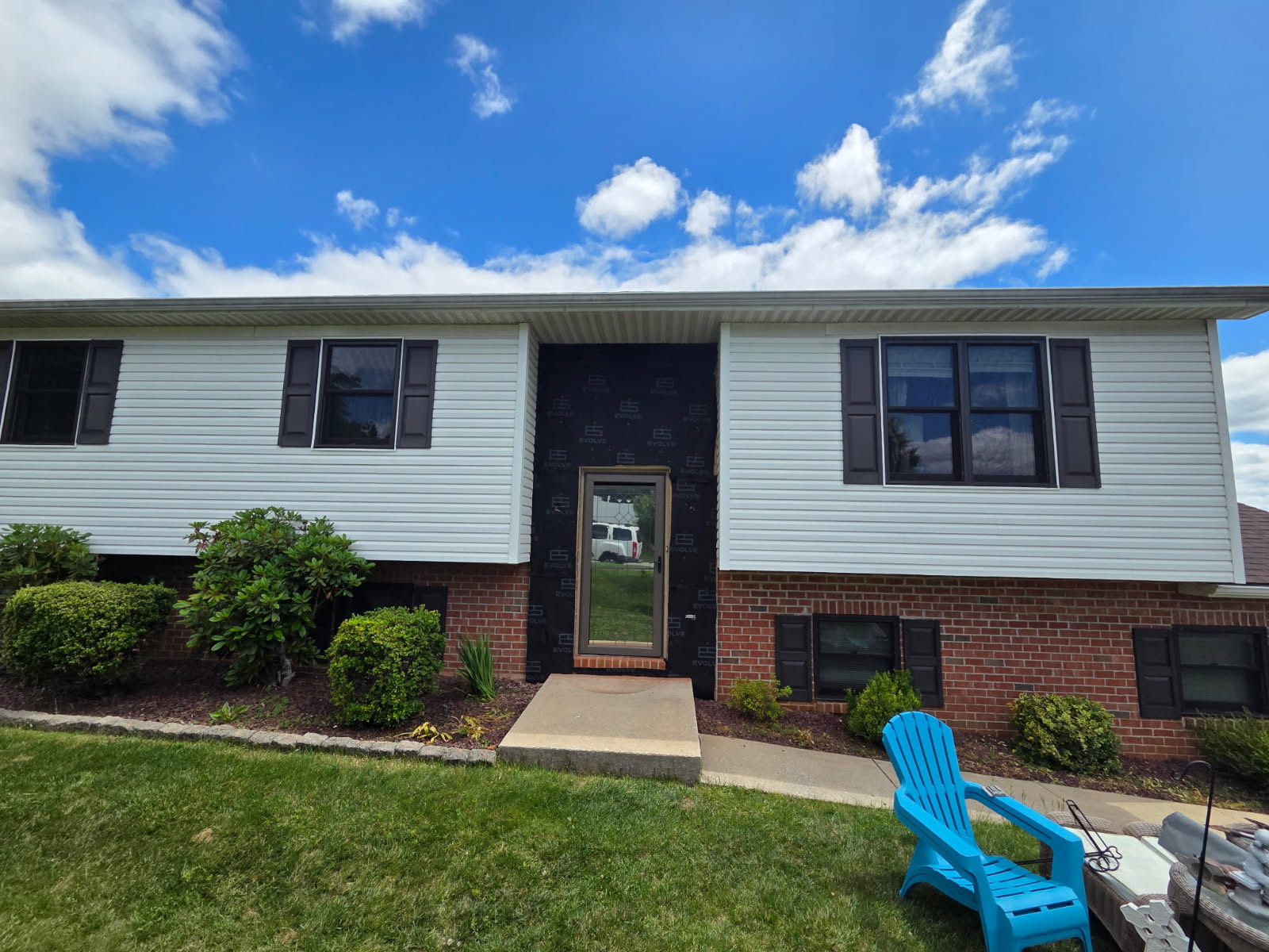 Split-level home with white siding, black shutters, and a re-done front entry