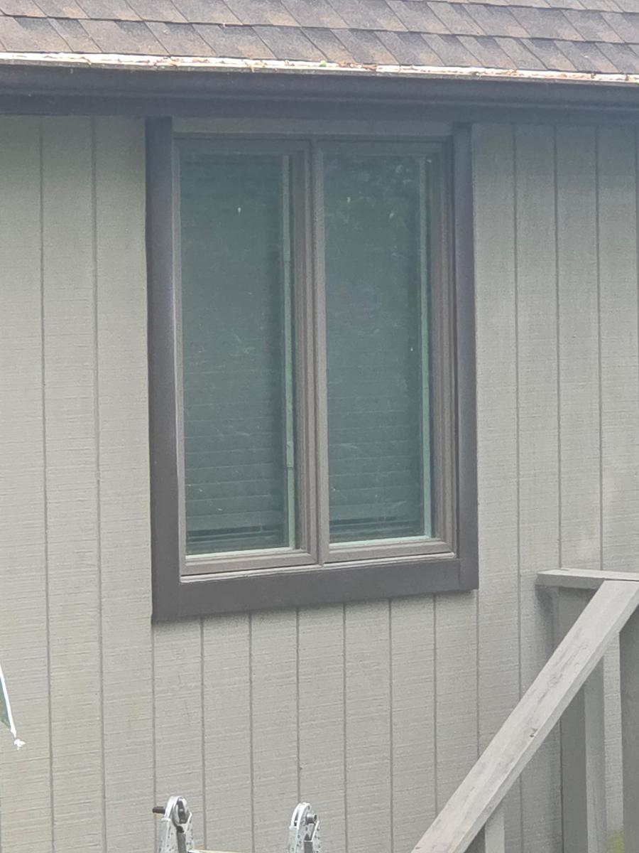 New window with fresh exterior trim on board-and-batten siding